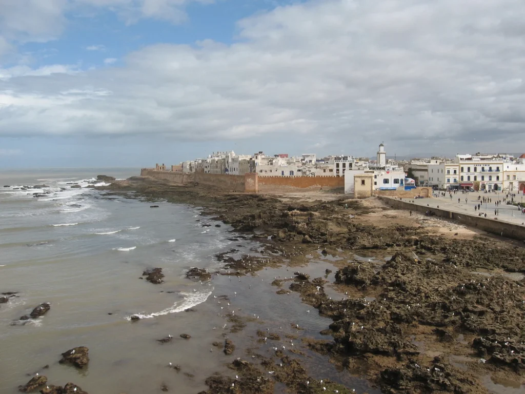 Essaouira's sea ramparts and white medina seen across the rocky shore