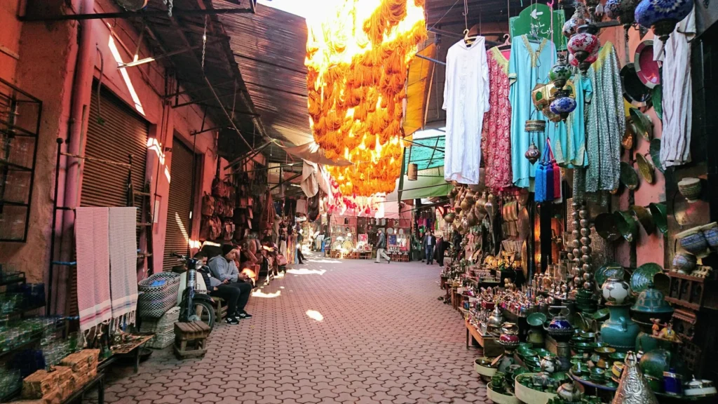 A covered souk lane in Marrakech lined with clothing and ceramic stalls